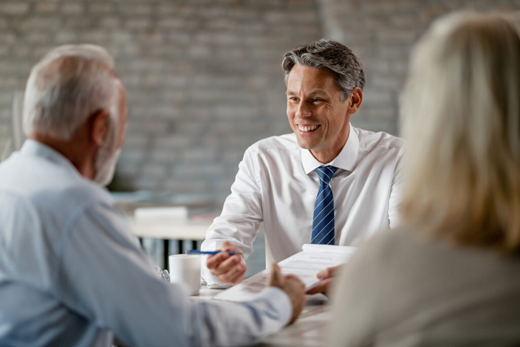 Happy bank manager talking with senior customers about terms of